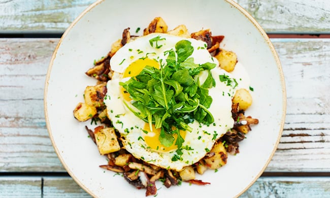 Truffle mushroom & sweet potato hash topped with two over-easy eggs, seasonal mushrooms and fresh greens