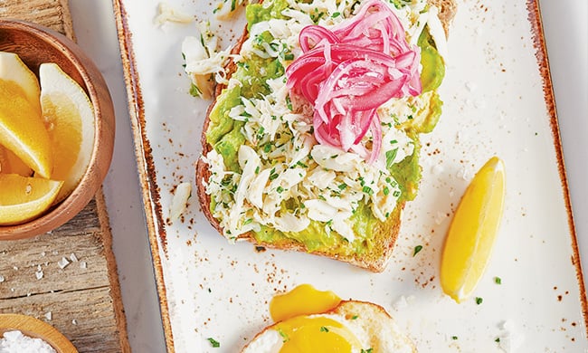 Crab avcocado toast with two over easy eggs, fresh lemon and sea salt