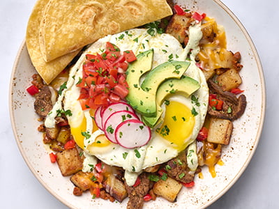 Thinly sliced carne asada, crumbled chorizo and diced red bell peppers in a potato hash topped with two cage-free eggs any style, Cheddar and Monterey Jack, housemade pico de gallo, fresh avocado, shaved radish, cilantro and jalapeño crema. Served with two warm wheat-corn tortillas.