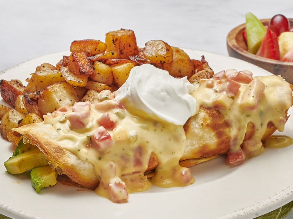 Whipped cage-free eggs with spicy, all-natural chicken breast, chorizo, green chiles, Cheddar and Monterey Jack, onions and avocado rolled in a flour tortilla. Topped with Vera Cruz sauce and all-natural sour cream. Served with fresh, seasoned potatoes.