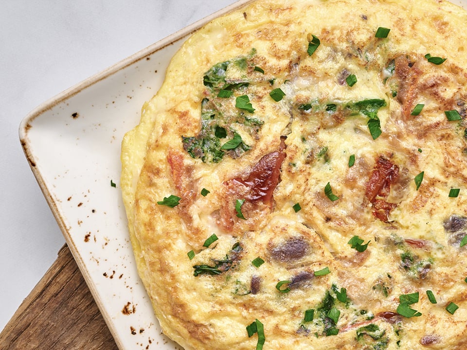 A classic Italian-style omelet with kale, house-roasted Crimini mushrooms, onions and tomatoes topped with Mozzarella and Parmesan. Served with ciabatta toast and lemon-dressed organic mixed greens.