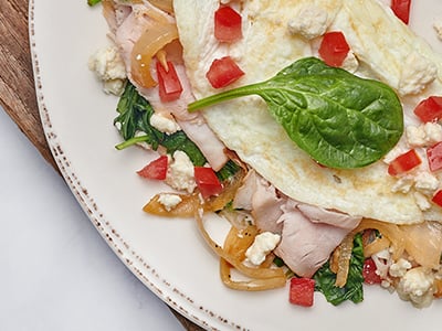 Turkey, house-roasted onions, tomatoes, spinach and Feta cheese in a cage-free egg white omelet. Served with sliced tomatoes and our whole grain artisan toast with all-natural house preserves.