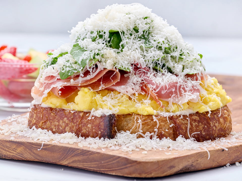 Thick-cut, griddled artisan sourdough with thinly shaved prosciutto, scrambled cage-free eggs, Monterey Jack, lemon-dressed arugula and roasted garlic aioli topped with freshly grated Parmesan. Served with a cup of fresh fruit.